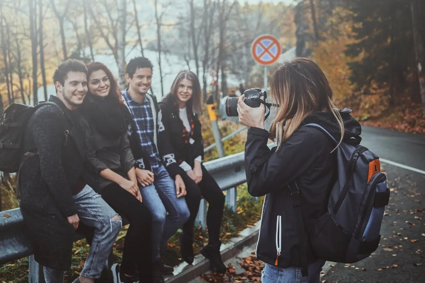 Eine junge Frau macht mit einer Digitalkamera ein Foto von ihren Freunden im Herbstwald.