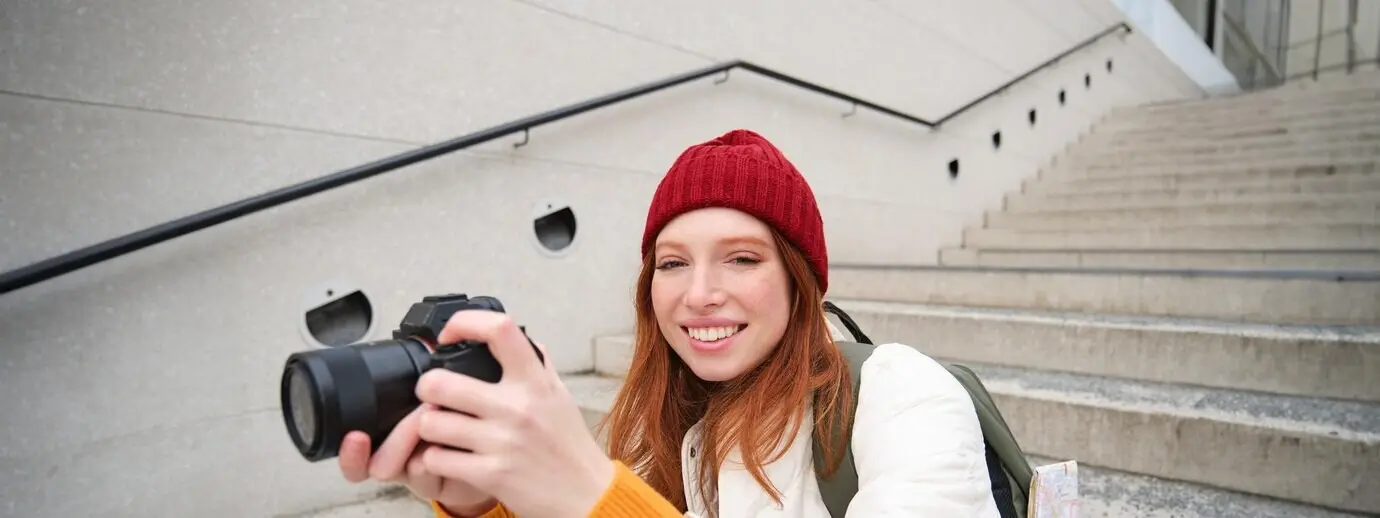 Porträt einer Fotografin, die mit einer professionellen Kamera durch die Stadt läuft und Fotos macht.